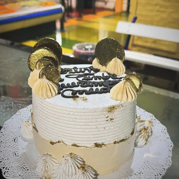 Torta blanca con detalles dorados y dedicatoria en chocolate